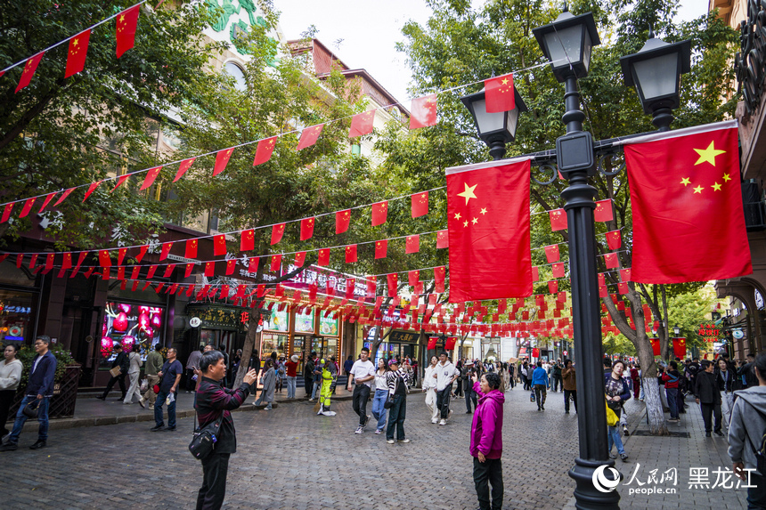 哈爾濱中央大街掛起了五星紅旗，許多市民游客在此拍照留念。人民網記者 張哲鑫攝